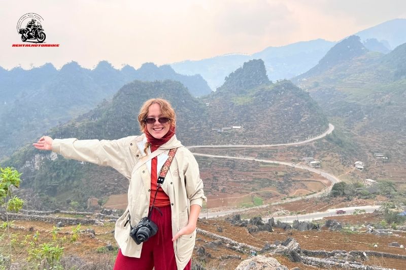 Female traveler posing with mountain road background in Ha Giang