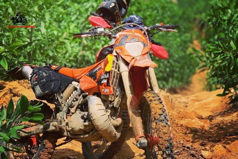 KTM dirt bike covered in mud on off-road trail in Vietnam