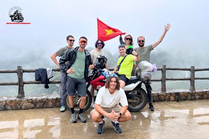 Foreign riders posing with Vietnamese flag on a motorbike tour