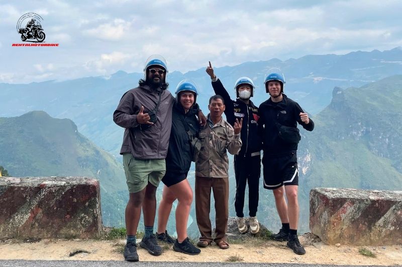 Group of bikers posing at mountain viewpoint