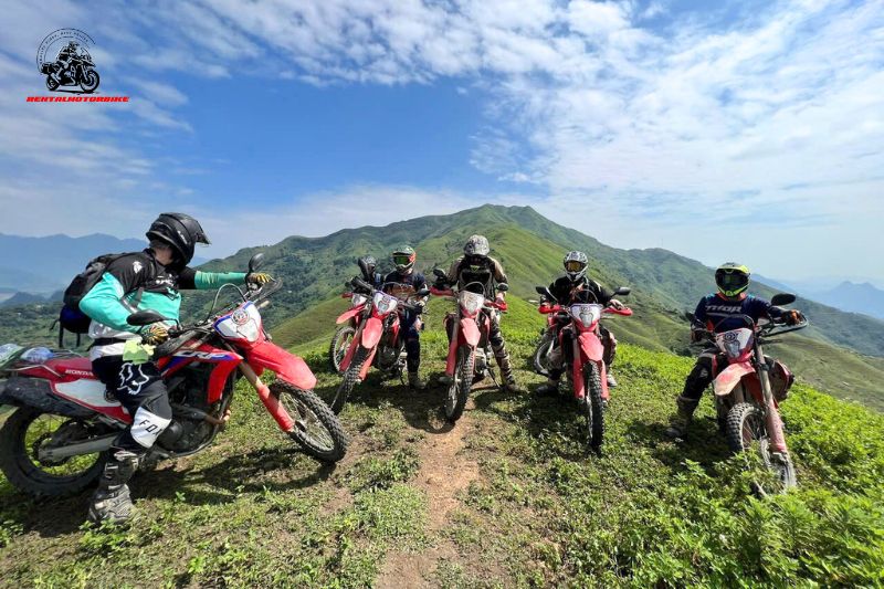 Dirt bikers on hilltop with clear blue sky