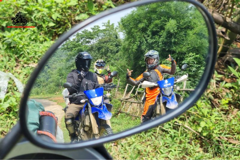 Group of riders seen through rearview mirror