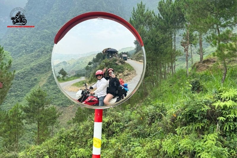 Couple riding motorbike, reflected in roadside mirror