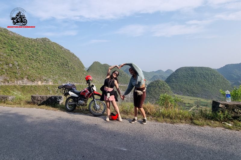 Two girls posing next to motorbike in the mountains
