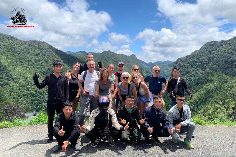 Group of tourists and guides posing on a mountain pass during motorbike tour