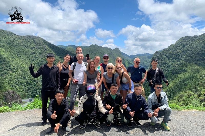 Tour group posing on a mountain pass with green hills behind