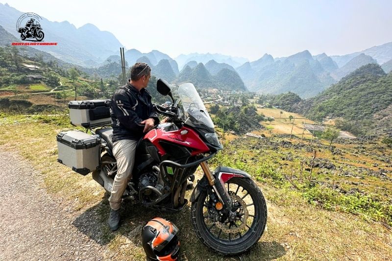 Rider resting on adventure bike with valley view