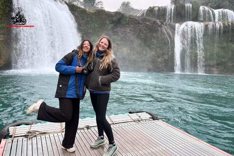Two women smiling by a stunning waterfall