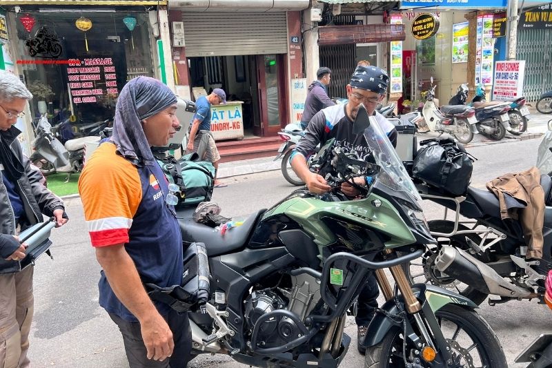 Men preparing a touring motorbike in front of a massage shop in Vietnam