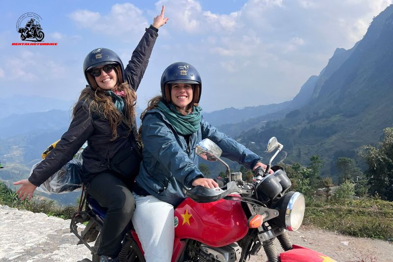 Two women posing on scooters on a dirt road
